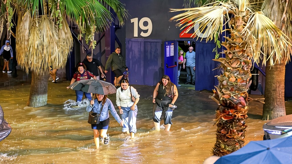 Vehículos detenidos en una calle inundada de Valencia bajo una intensa tormenta nocturna.