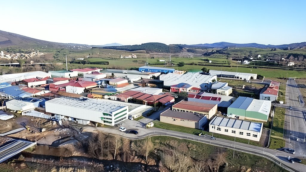 Vista aérea de un polígono industrial y empresarial en Cantabria, con naves industriales y almacenes bajo un cielo despejado.