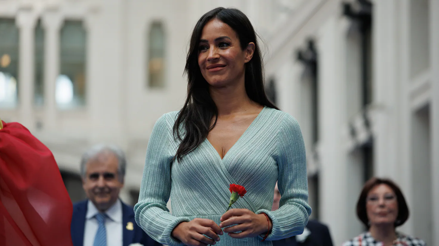 Fotografía editorial de Begoña Villacís sonriendo mientras sostiene un clavel rojo.