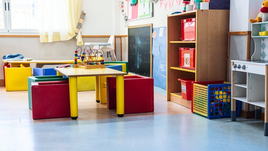 Fotografía de una guardería infantil con juguetes y mobiliario escolar de colores.