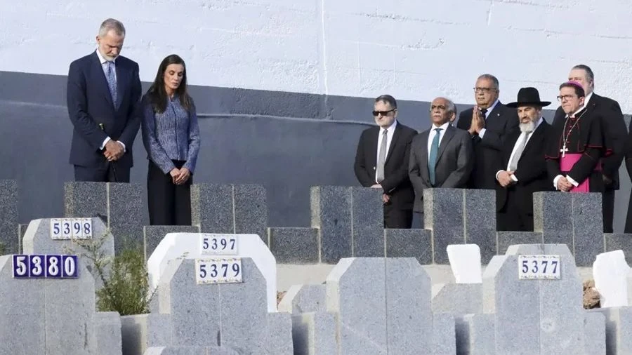 Fotografía editorial que muestra a los Reyes de España, Felipe VI y Letizia, junto a representantes religiosos locales rindiendo homenaje en un cementerio durante su visita institucional a Ceuta.