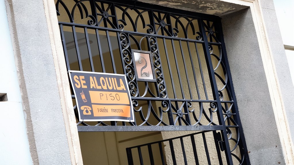 Cartel de 'se alquila piso' colgado en la verja de hierro de un portal
