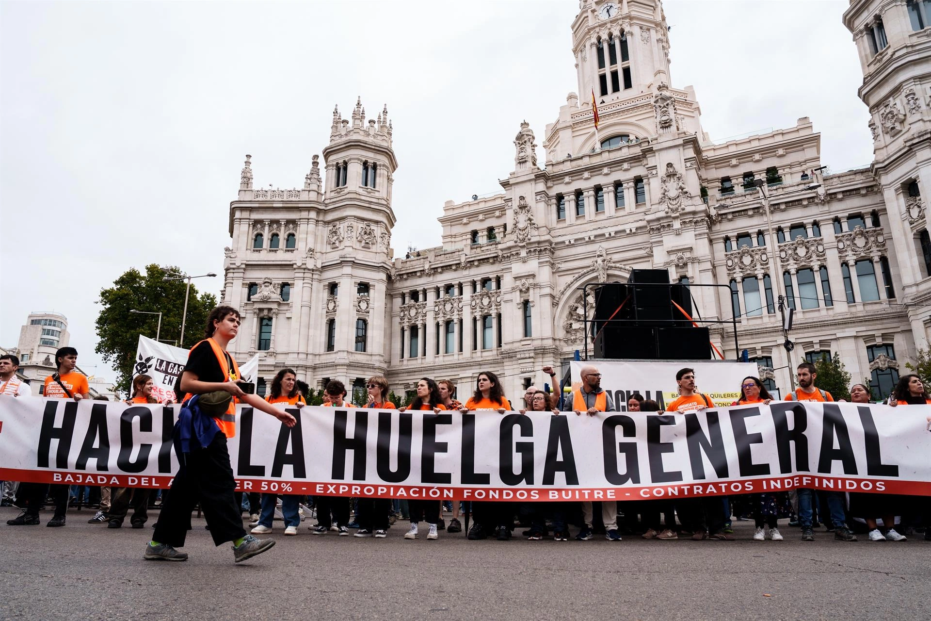 Manifestantes sostienen una gran pancarta con el lema 'HACKEA LA HUELGA GENERAL' frente al Palacio de Cibeles en Madrid durante una protesta por la vivienda.