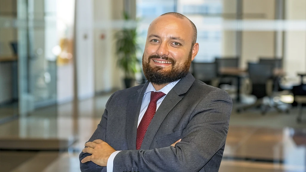 Fotografía corporativa de Raúl Florido, abogado especializado en protección de datos y nuevas tecnologías, en una oficina moderna con los brazos cruzados y sonriendo a la cámara.
