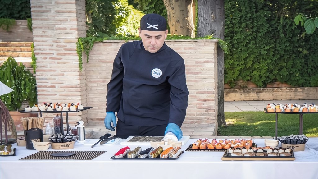 Un sushiman preparando sushi en una mesa de catering al aire libre para Sibuya Events and Organization.