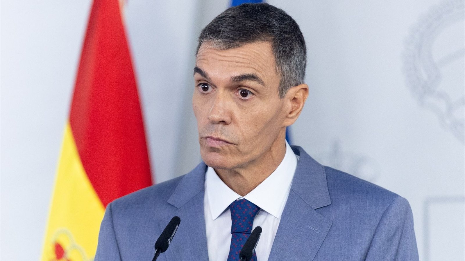 Fotografía del presidente del Gobierno de España, Pedro Sánchez, compareciendo en una rueda de prensa con una bandera de España al fondo.